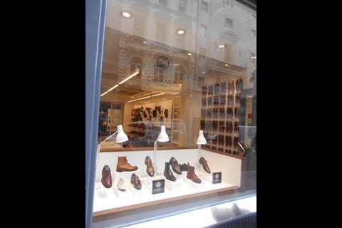 In the store window a selection of men’s shoes are set in an open-fronted white box with white Anglepoise lights, acting as props and light source, behind them.